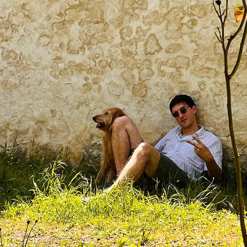Samy adossé à un mur de pierre, dans l'herbe, avec Lucy
